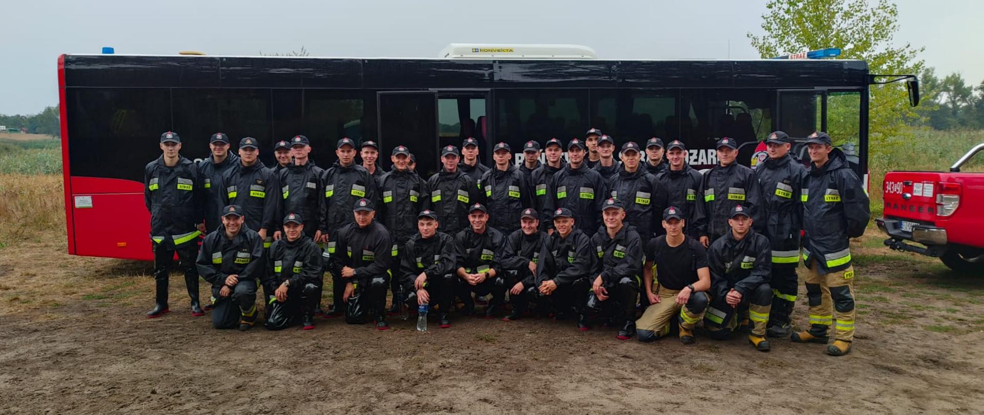 Zdjęcie grupowe kadetów Centralnej Szkoły PSP (30 osób) w towarzystwie dwóch dowódców oraz kierowcy na tle autokaru PSP
