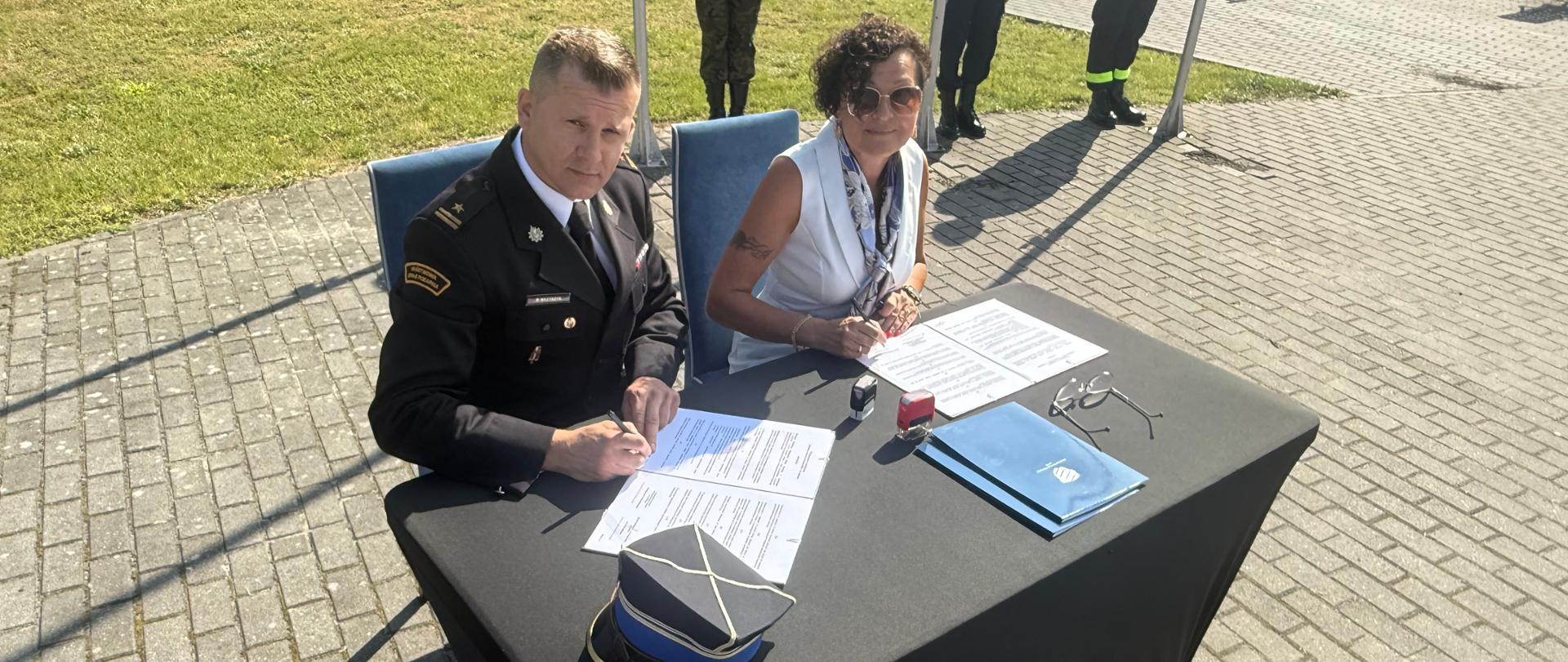 Dyrektorka szkoły Edukacja Lubasz i Komendant Powiatowy PSP w Czarnkowie podpisują dokumenty podczas inauguracji roku szkolnego.