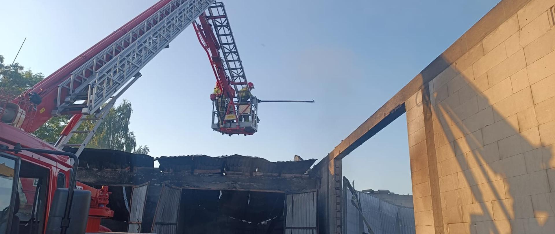 Strażacy stoją w koszu podnośnika.