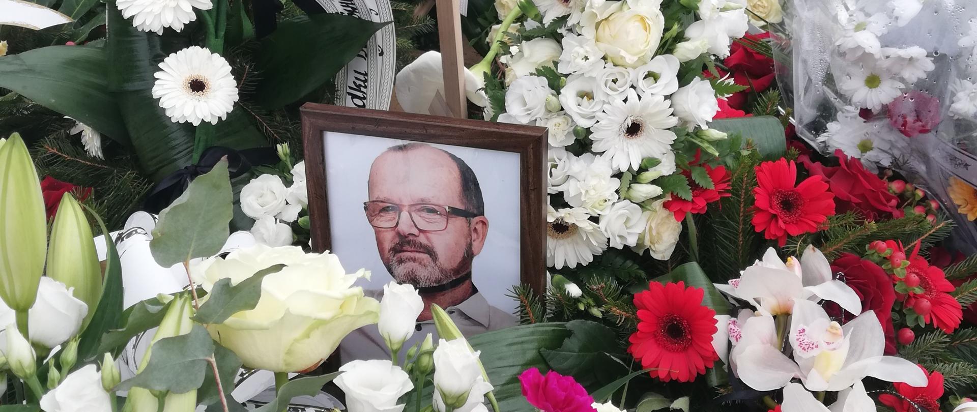 Zdjęcie Naczelnika OSP w Mosinach na tle kwiatów.