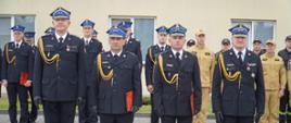 Dwóch funkcjonariuszy Komendy Powiatowej Państwowej Straży Pożarnej w Rypinie stoi w rzędzie po odebraniu nagrody Komendanta Wojewódzkiego. Po ich lewej stronie stoi Komendant Powiatowy Państwowej Straży Pożarnej w Rypinie, a po prawej Kujawsko-pomorski Komendant Wojewódzki Państwowej Straży Pożarnej. 