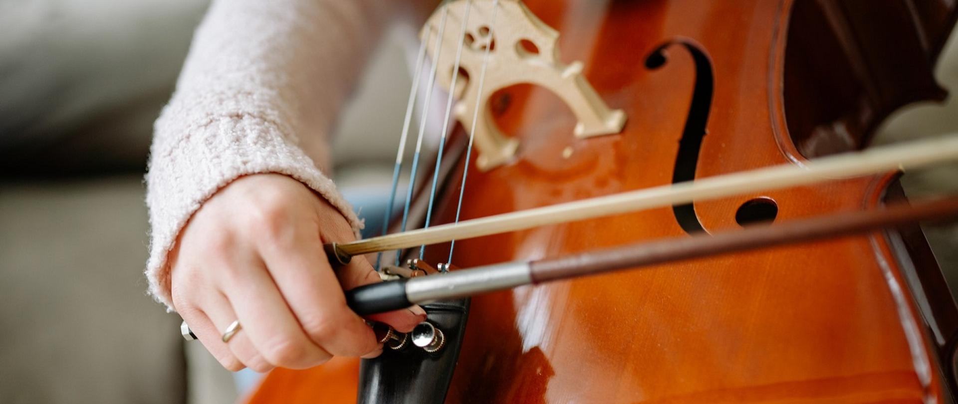 Zdjęcie przedstawia zbliżenie na dłoń grającej wiolonczelistki