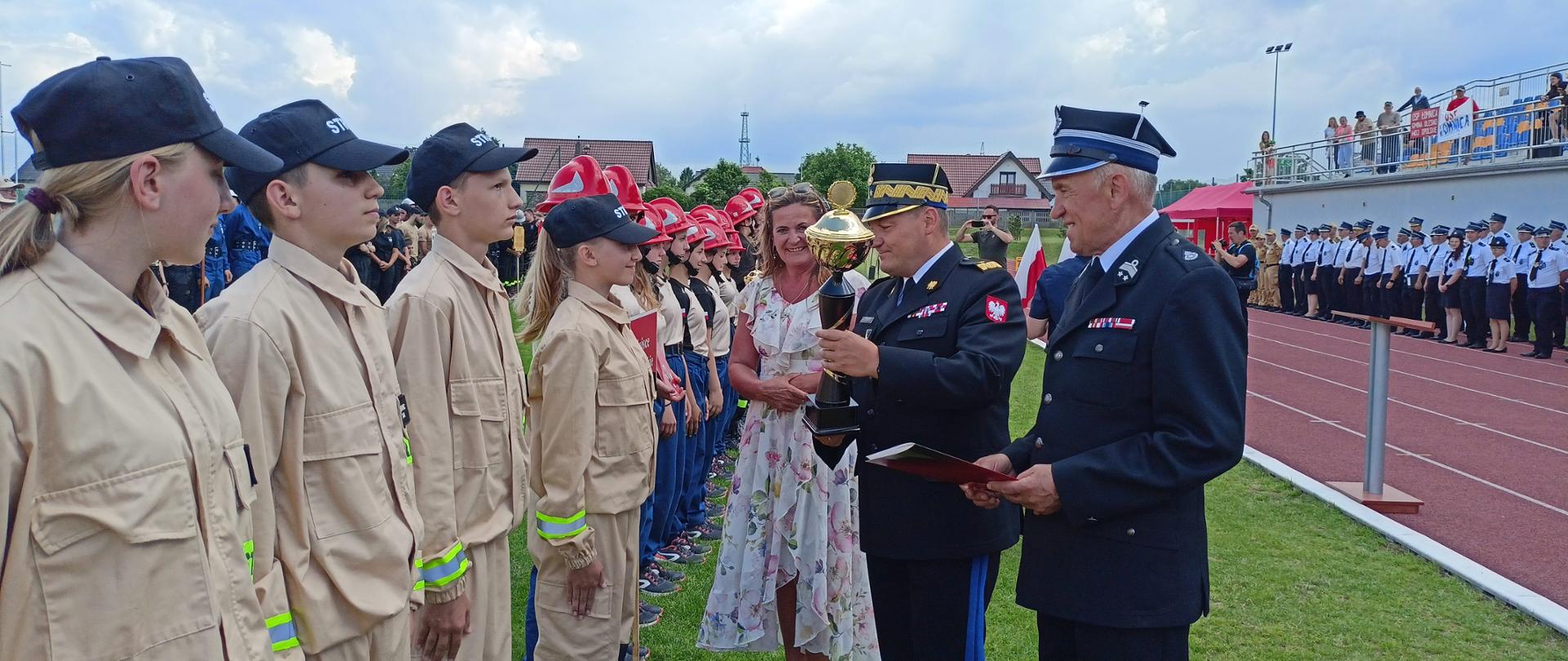 Młodzieżowa Drużyna Pożarnicza odbiera puchar od Komendanta Wojewódzkiego i Prezesa OSP.