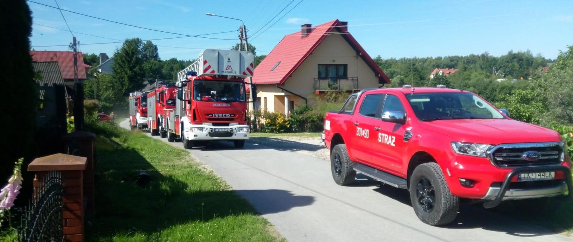 Zdjęcie przedstawia drogę na której zaparkowały samochody pożarnicze biorące udział w zdarzeniu.