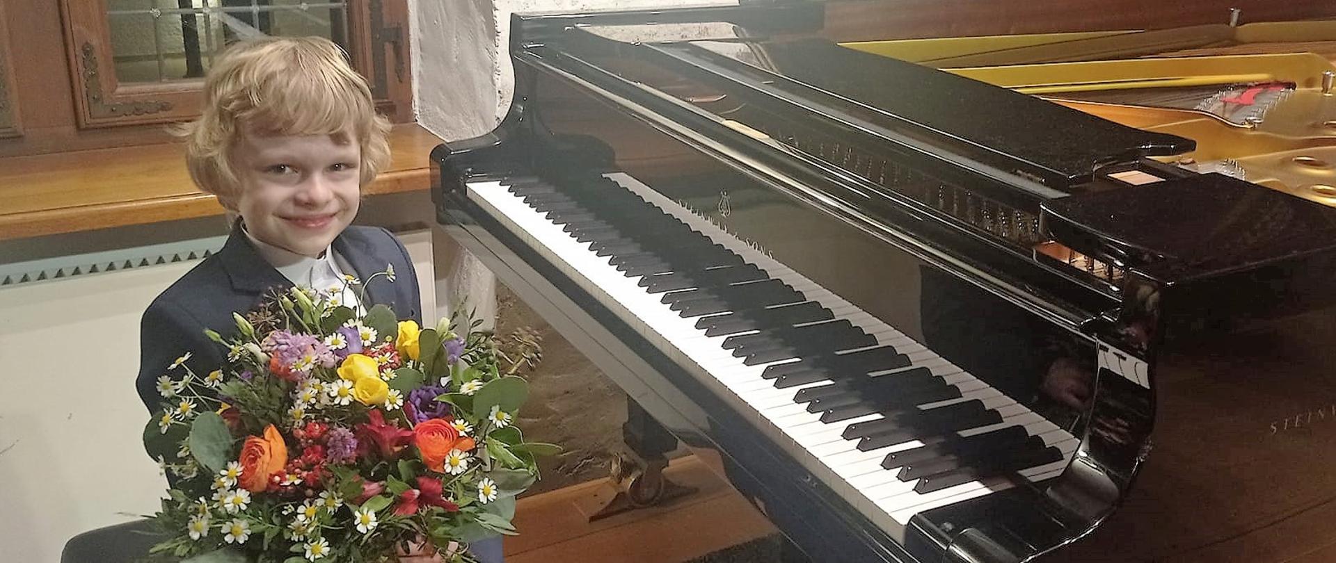 chłopiec z bukietem kwiatów siedzący przy fortepianie
