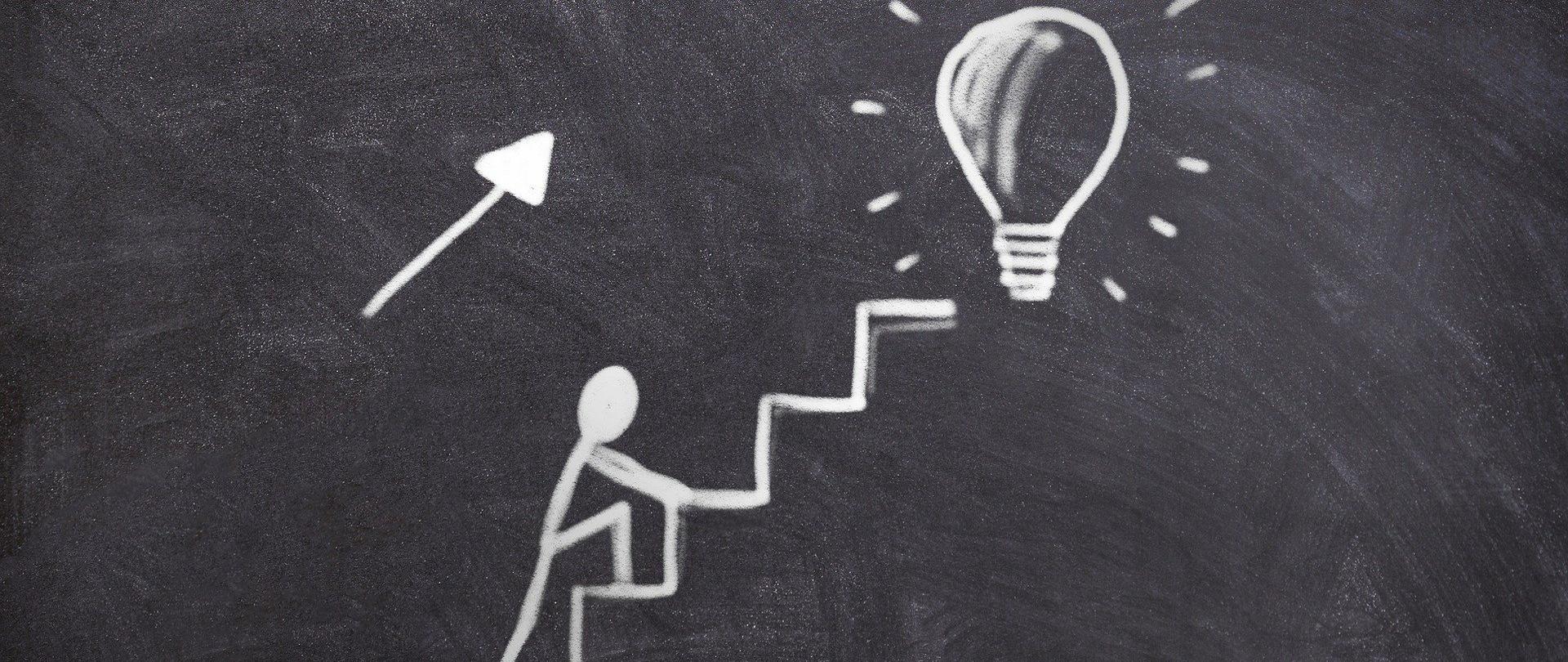 zdjęcie symboliczne przedstawiające osobę wchodzącą po schodach, na szczycie jest żarówka
