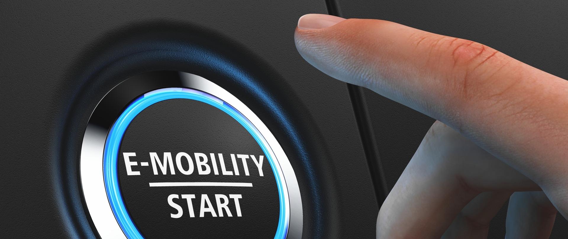 Przycisk z napisem "E-mobility Start" i osoba, która zaraz go wciśnie.