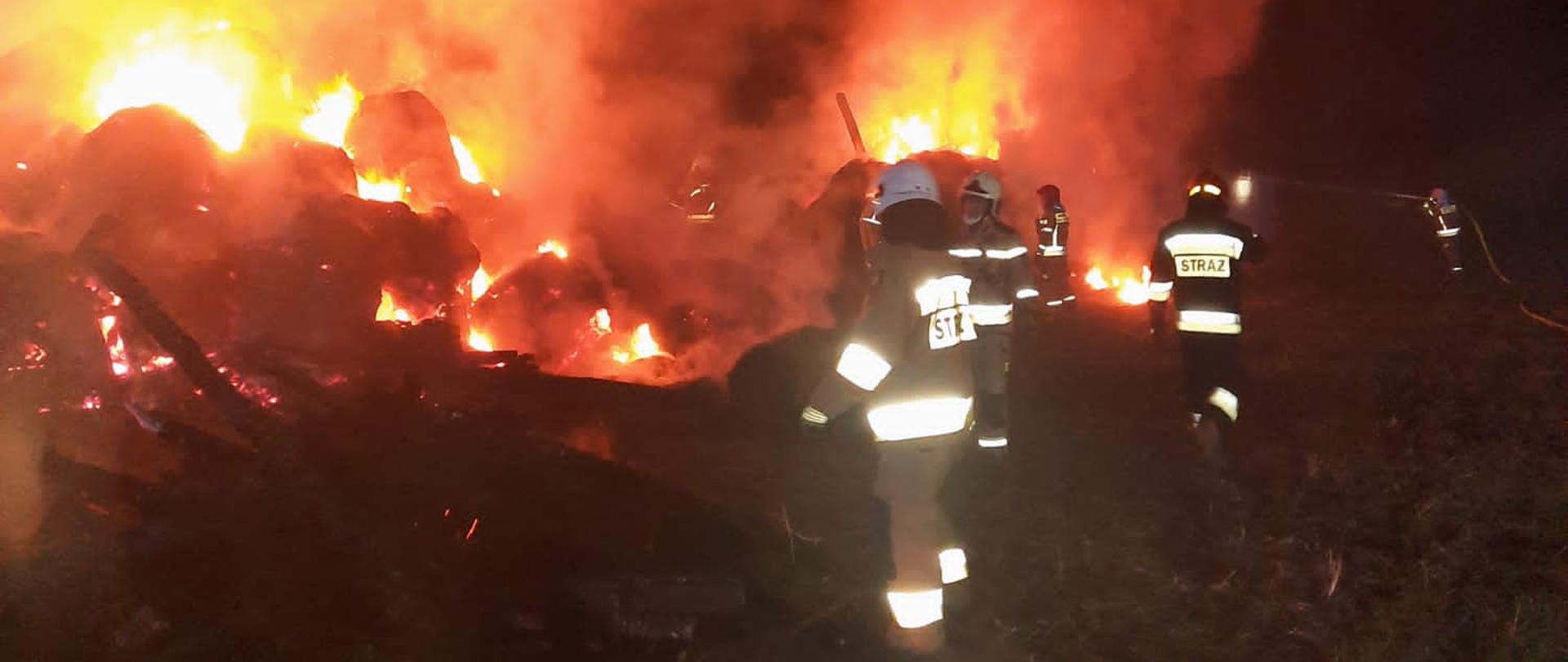 Zdjęcie przedstawia strażaków w akcji gaszenia pożaru stodoły.