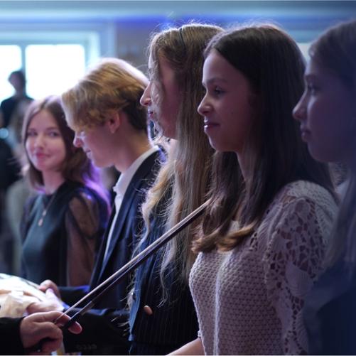 Zdjęcie przedstawia uczniów ZPSM i zaproszonych gości, biorących udział w Pasowaniu Uczniów klas 1. PSM I i II st. w Dniu Muzyki 2022