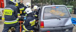 strażacy podczas próby ewakuacji osoby poszkodowanej z samochodu osobowego w trakcie założenia egzaminacyjnego