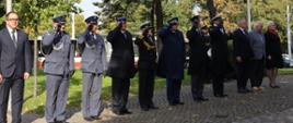 Funkcjonariusze służb mundurowych oddają honory a osoby cywilne stoją na baczność.