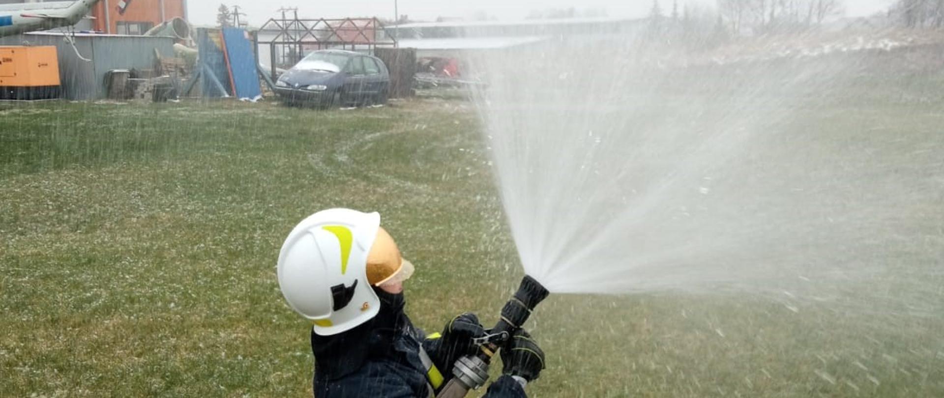 Zdjęcie przedstawia jeden z elementów egzaminu praktycznego szkolenia podstawowego strażaka ratownika Ochotniczych Straży Pożarnych, realizowanego w Komedzie Powiatowej Państwowej Straży Pożarnej w Gołdapi, polegającego na weryfikacji umiejętności i znajomości w zakresie prowadzenia działań gaśniczych (w szczególności w formie operowania prądami wody)