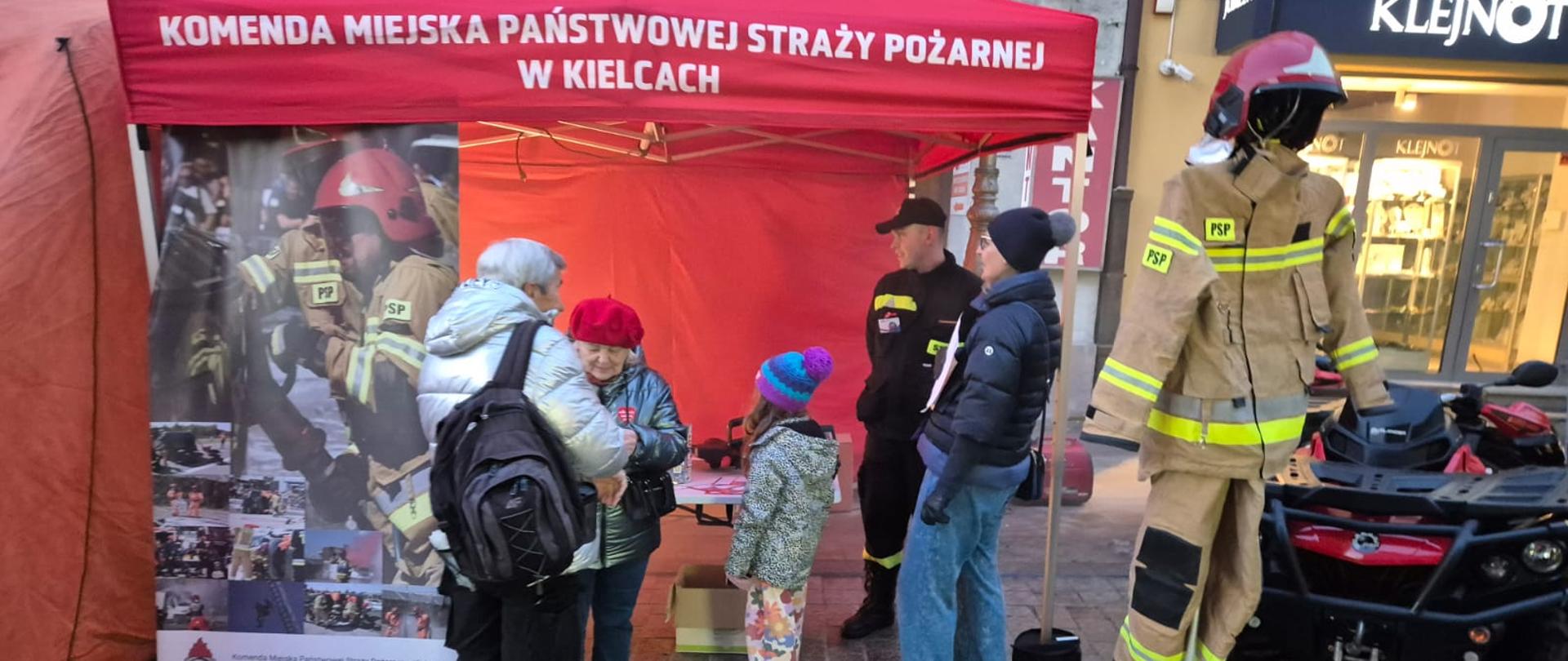 Zdjęcie przedstawia stoisko Komendy Miejskiej PSP w Kielcach: po prawej strażacki quad i mundur strażaka, po lewej namiot i zwiedzających.