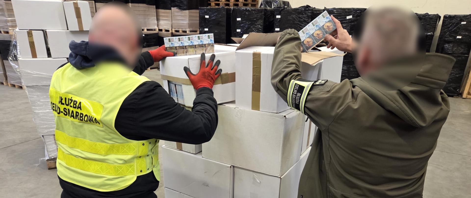 Dwie osoby stoją przy kartonach w magazynie, sprawdzają zawartość kartonów.