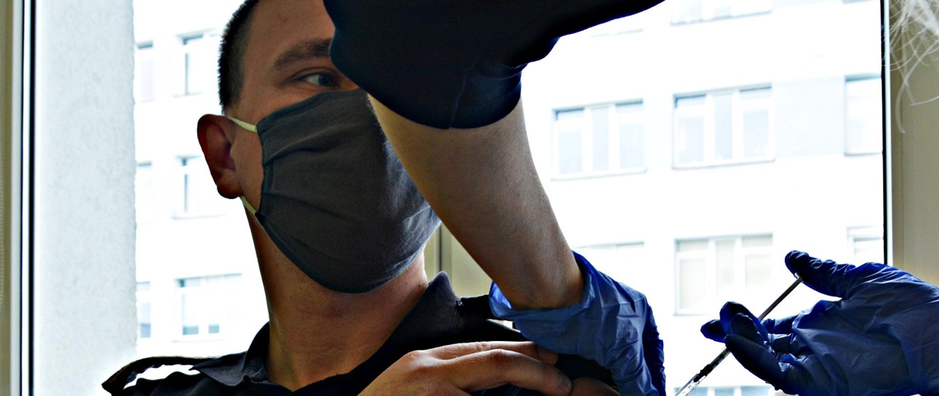 Na zdjęciu widać podawanie w ramię szczepionki dla strażaka.