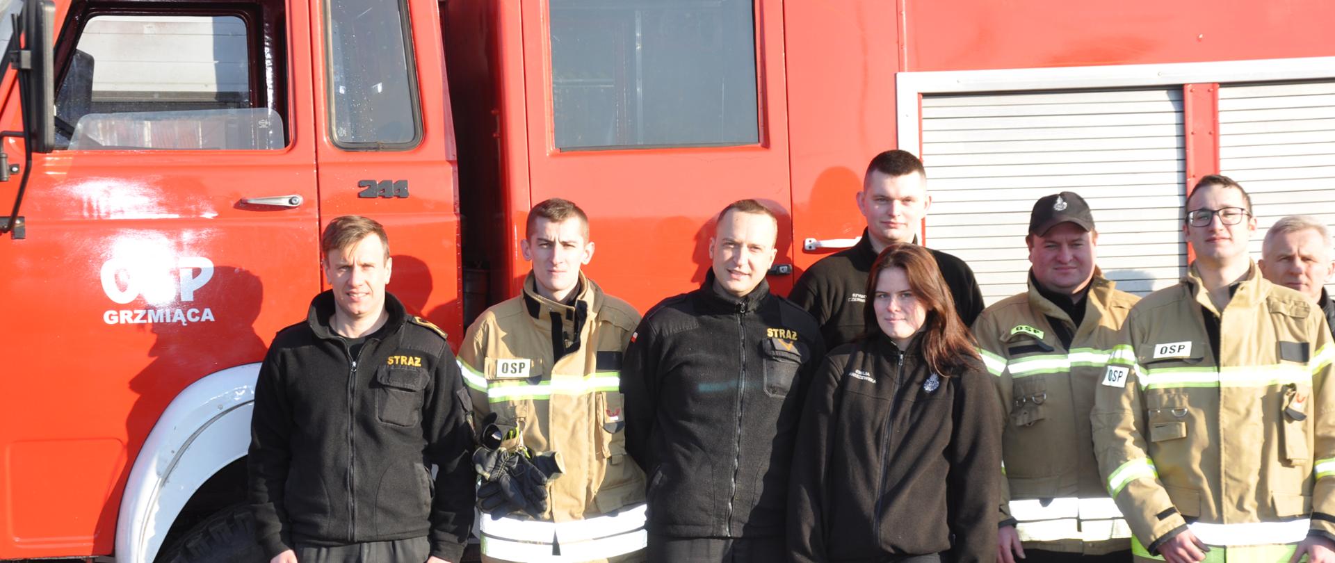 Na tle samochodu gaśniczego ochotnicy z OSP Grzmiąca oraz strażacy z KP PSP w Brzezinach