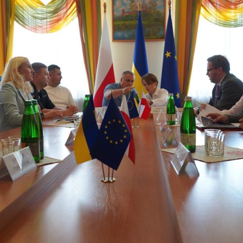 Przy stole siedzi kilka osób, w tym pełnomocnik rządu Jadwiga Emilewicz. Na stole flagi Polski, Ukrainy i UE