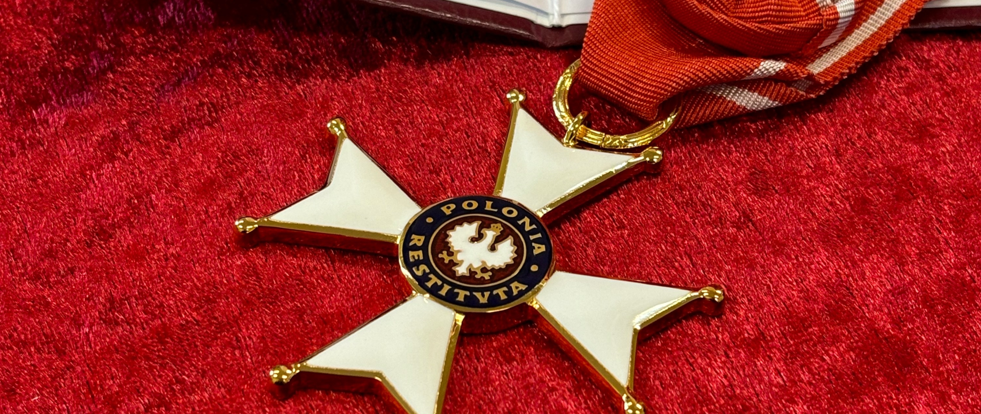 medal leżący na czerwonej poduszce i książeczką z nazwiskiem uhonorowanego