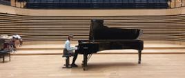 Uczennica grająca na fortepianie na scenie sali koncertowej PSM