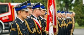 Pododdział strażaków oraz sztandar w umundurowaniu galowym stoją podczas uroczystości