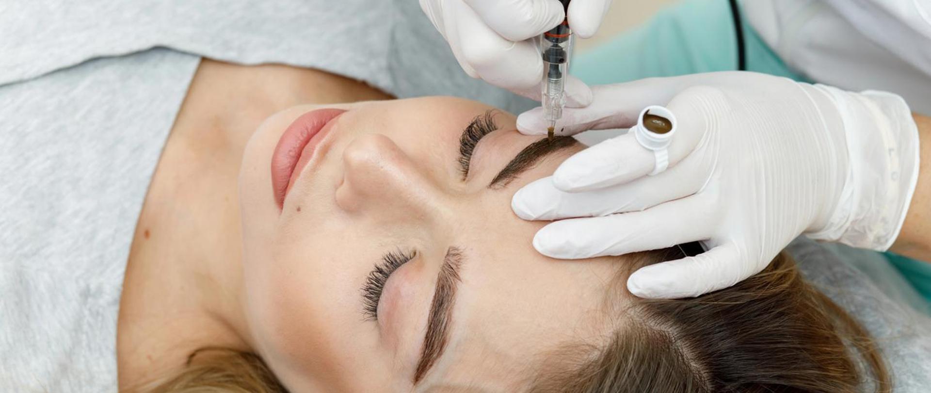 na zdjęciu twarz leżącej kobiety, na której brwiach wykonywany jest tatuaż permanentny