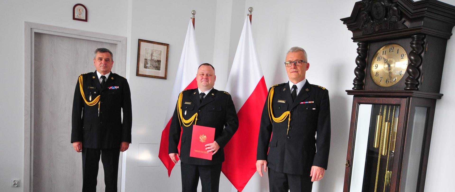 Zdjęcie przedstawia pomorskiego komendanta wojewódzkiego Państwowej Straży Pożarnej, nowego zastępcę komendanta powiatowego PSP wraz z komendantem powiatowym PSP w Malborku , stojących po wręczeniu decyzji.