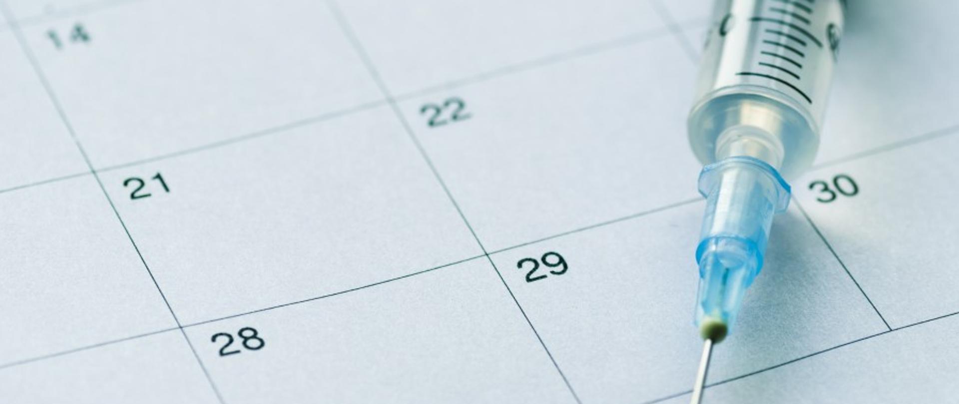 Zdjęcie, na którym widnieje kalendarz wraz ze strzykawką.