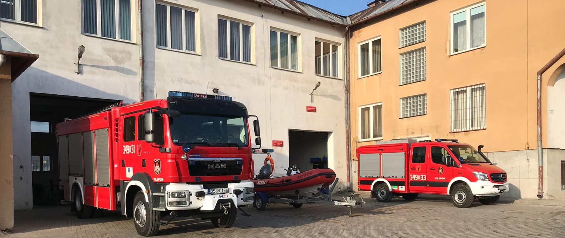 Zdjęcie przedstawia dwa samochody pożarnicze oraz łódź na przyczepce w tle budynek strażnicy OSP w Filipowie budynek jest dwukondygnacyjny o spadzistym dachu