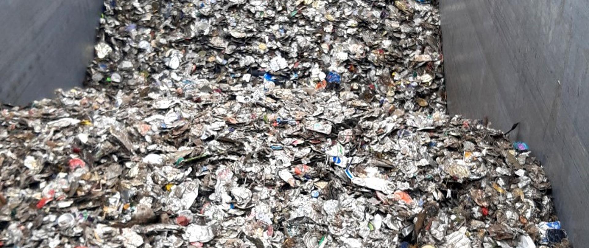 Naczepa TIR-a. W naczepie odpady w postaci zgniecionych, metalowych opakowań.