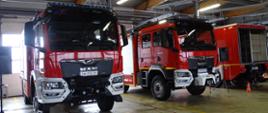 Na zdjęciu widać dwa samochody strażackie koloru czerwonego. Samochody no nowe pojazdy pozyskane dla jednostek z Komendy Miejskiej Państwowej Straży Pożarnej w Jeleniej Górze. Zdjęcie wykonane w hali. 