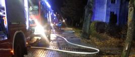 Zdjęcie przedstawia samochody pożarnicze z rozwiniętą linią gaśniczą