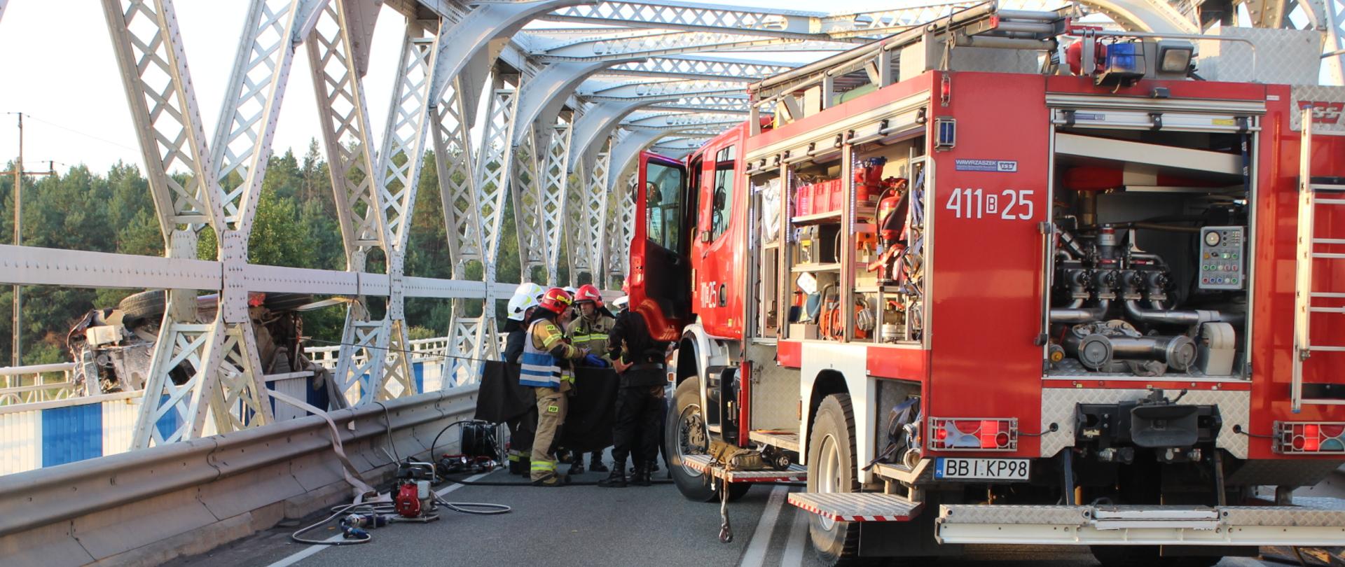 Samochód ratowniczo gaśniczy zabezpieczający (stabilizacja pojazdu) przy użyciu linki rozbity samochód osobowy podczas działań ratowniczo-gaśniczych w pobliżu miejscowości Ploski