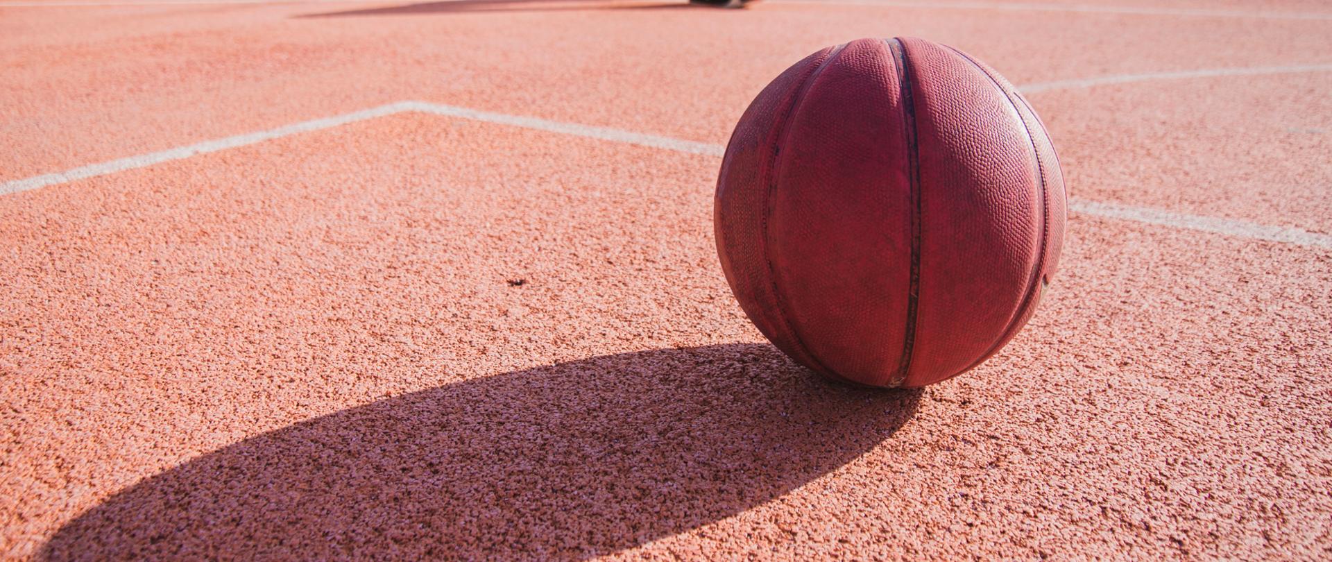 Zdjęcie przedstawiające podłoże boiska sportowego, piłkę do koszykówki 