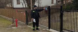 Akcja informacyjna na temat szczepień przeciwko COVID-19 strażak wrzuca ulotkę do skrzynki pocztowej