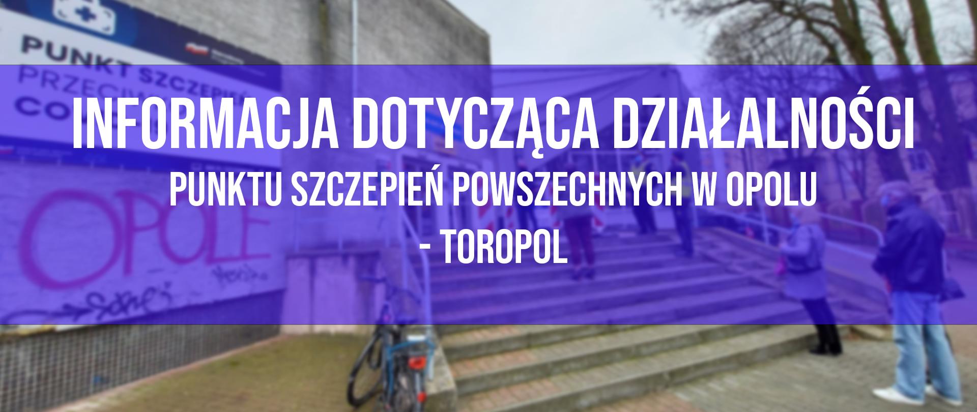 Zdjęcie przedstawia w tle punkt szczepień powszechnych w Opolu. Widać jasny budynek, a przed nim schody, na których w kolejce stoją mieszkańcy regionu. Ci, czekają na szczepienia przeciwko Covid-19. Po lewej stronie kadru, tuz przy schodach widać niebieski rower, przymocowany do balustrady od schodów. W skrajnej części kadru po lewej stronie, na fasadzie budynku widać napis Opole oraz - powyżej - baner z napisem Punkt Szczepień Powszechnych. Po prawej, skrajnej stronie kadru w tle widać konary drzew.
Centralnie na środku rozmytego zdjęcia widać granatowy półprzeźroczysty zarys prostokąta, na którym napis: Informacja dot. dalszej działalności Powszechnego Punktu Szczepień.