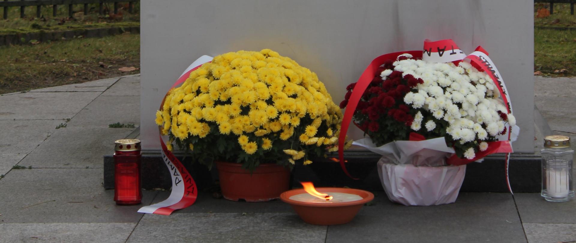 Kwiaty, znicz pod pomnikiem
