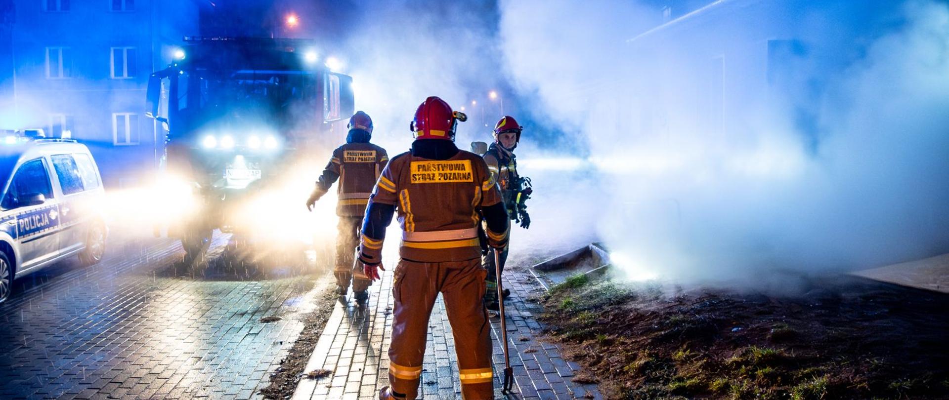 Strażacy przygotowują się do wejścia do pożaru, widoczne duże zadymienie