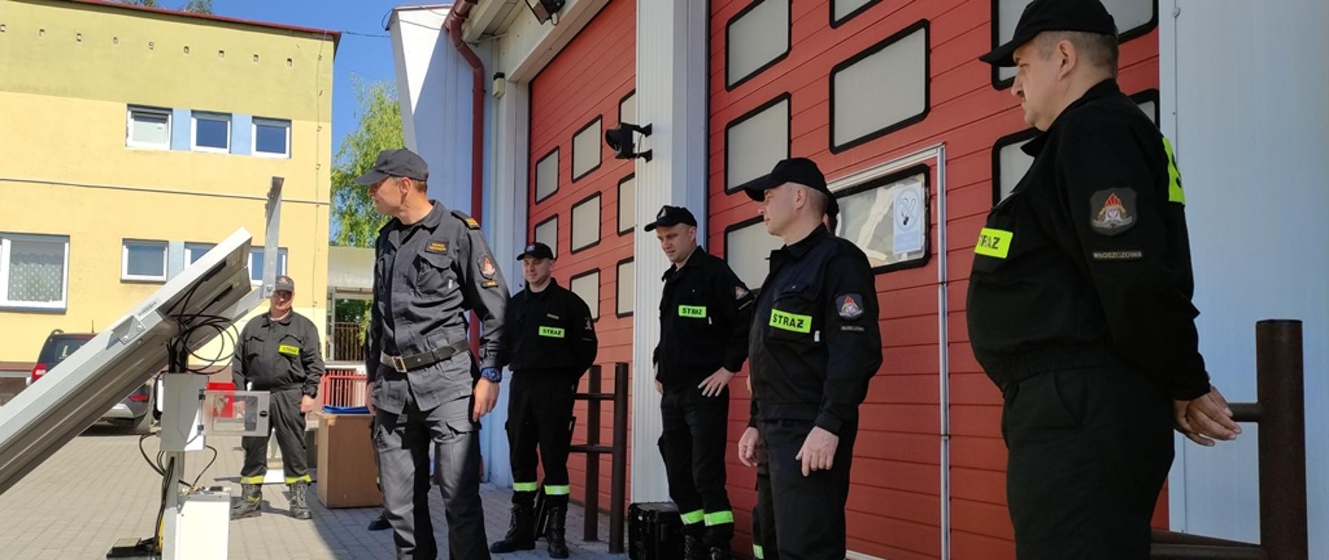 Plac wewnętrzny komendy powiatowej, konstrukcja wsporcza oraz zainstalowane na niej panele fotowoltaiczne, strażacy JRG Włoszczowa oraz prowadzący szkolenie funkcjonariusze ośrodka szkolenia komendy wojewódzkiej 