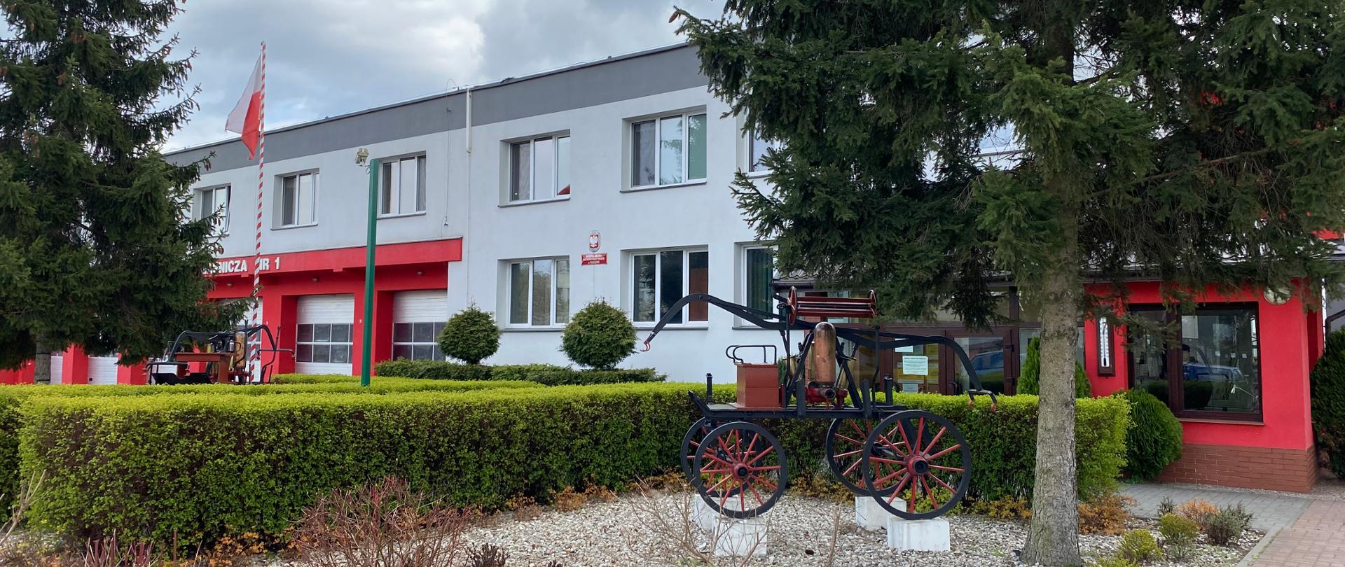 Siedziba KM PSP we Włocławku - widok od frontu. Na pierwszym planie stara, zabytkowa sikawka, w tle widać bramy garażowe.