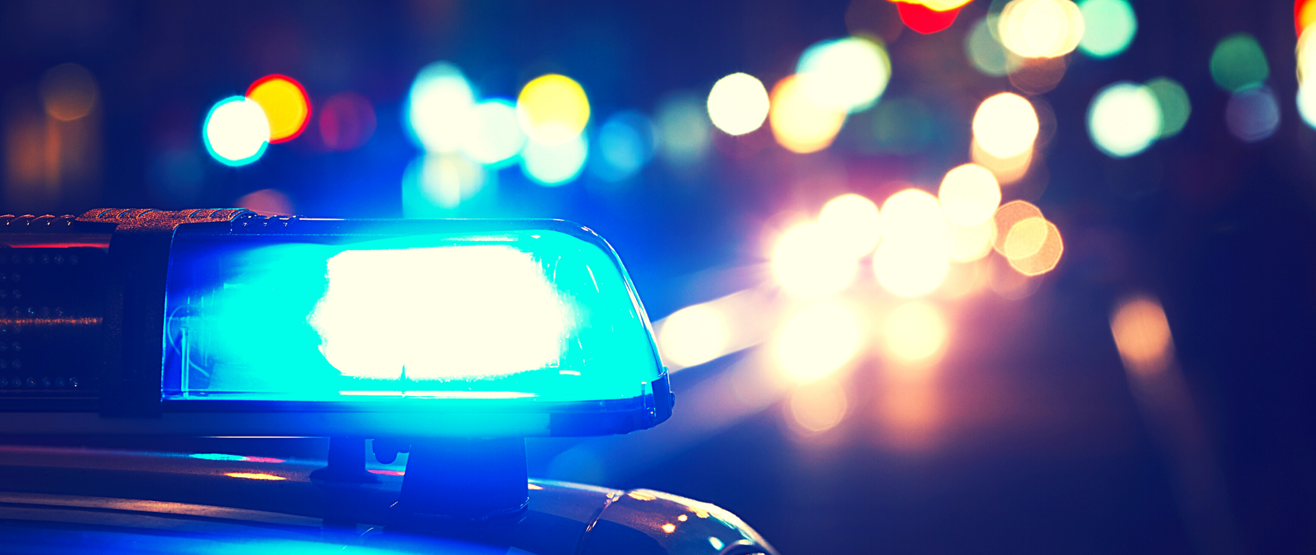 Ulica - na pierwszy planie lampa radiowozu policyjnego, w tle rozmazane światła aut
