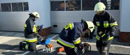 Przygotowanie sprzętu do prac technicznych – strażacy sprawdzają pilarki na placu jednostki.