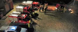 POSZUKIWANIA ZAGINIONEJ STARSZEJ OSOBY
Zdjęcie przedstawia strażaków szykujących się do poszukiwań nocnych zaginionej osoby oraz samochody strażackie.
W tle plac Komendy oraz budynki.
