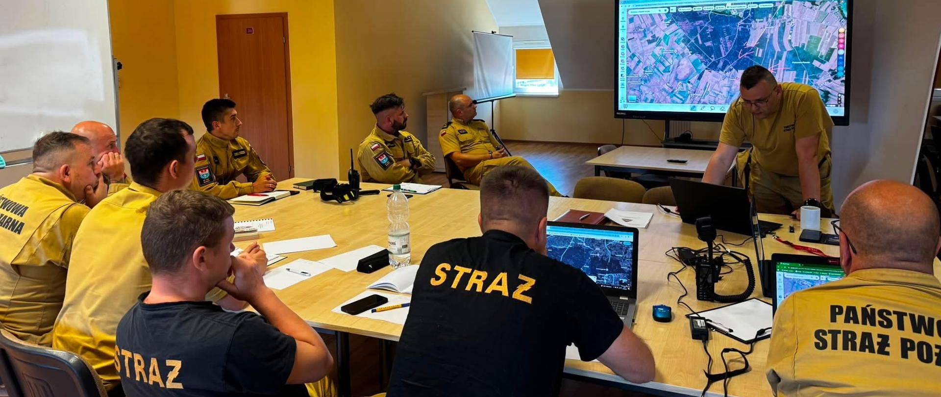 Zdjęcie przedstawia strażaków pracujących w sztabie.