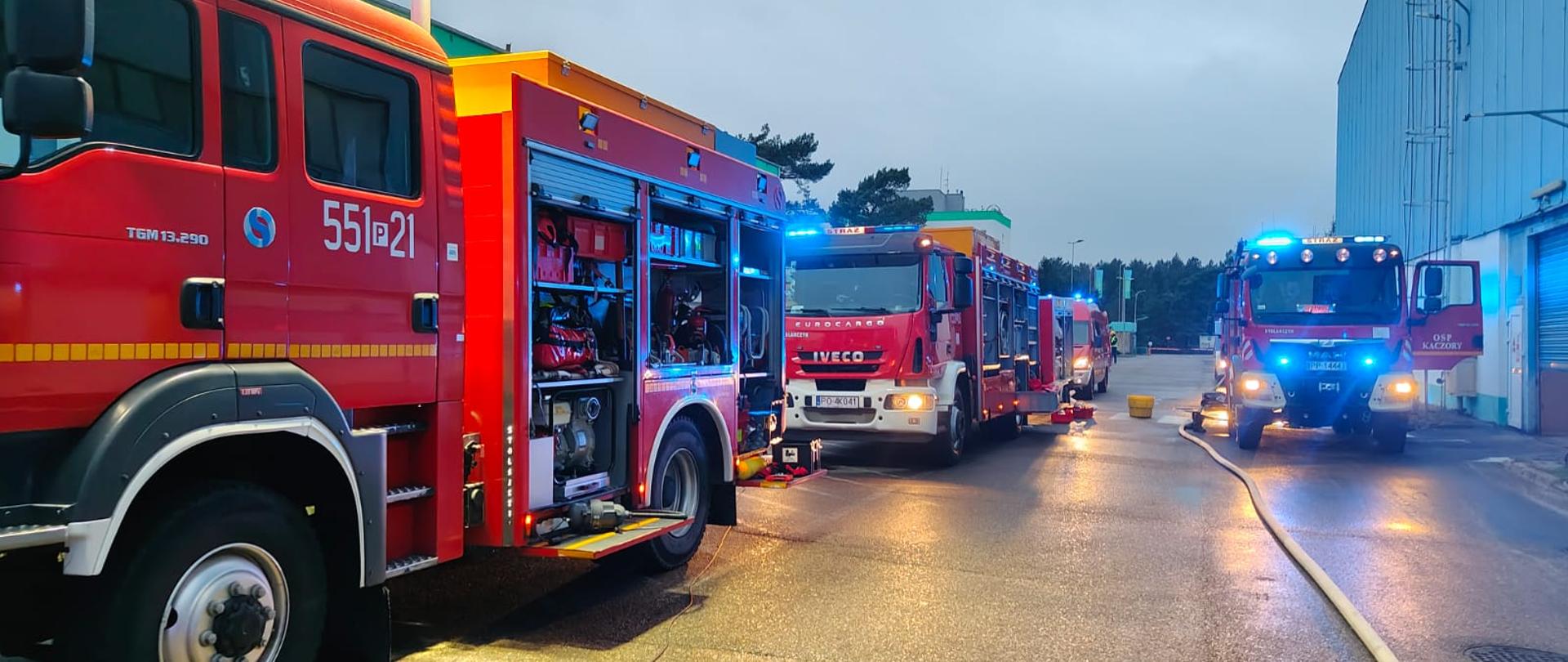Na zdjęciu widać strażaków w trakcie ćwiczeń chemicznych. Jest ciemno, ćwiczenia odbywają się na zewnątrz. 