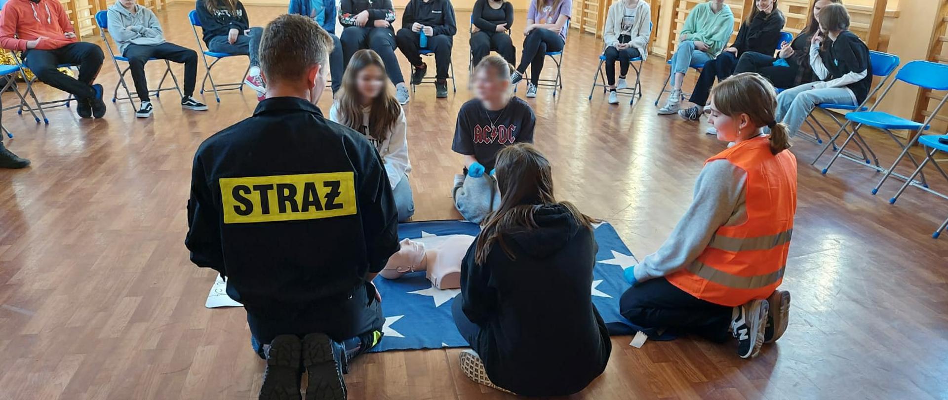 Funkcjonariusz tut. Komendy przedstawia podstawowe zasady udzielania pierwszej pomocy na fantomie szkoleniowym