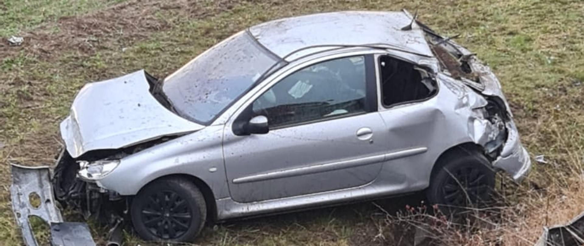 Widać uszkodzony samochód osobowy na łące, który zjechał z drogi