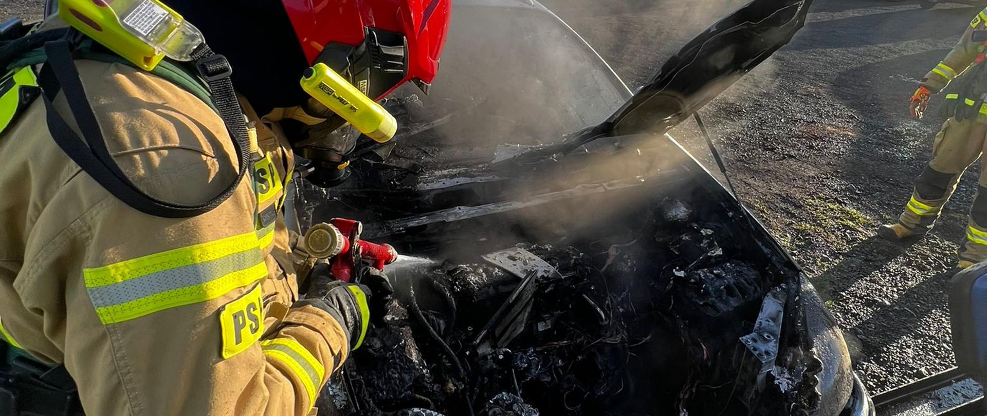 Na zdjęciu widać strażaka gaszącego pożar pojazdu osobowego 