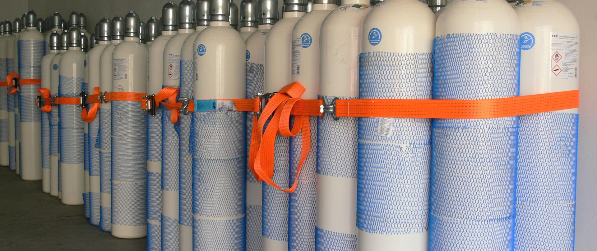 Na zdjęciu widoczne ustawione w magazynie butle z tlenem