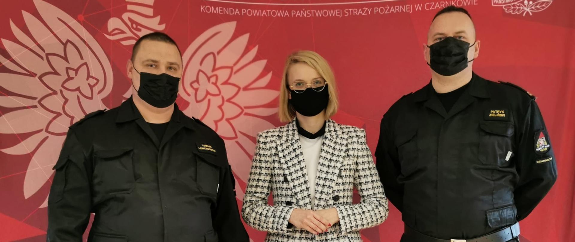 Funkcjonariusze z Panią Poseł stoją na tle baneru Komendy Powiatowej.