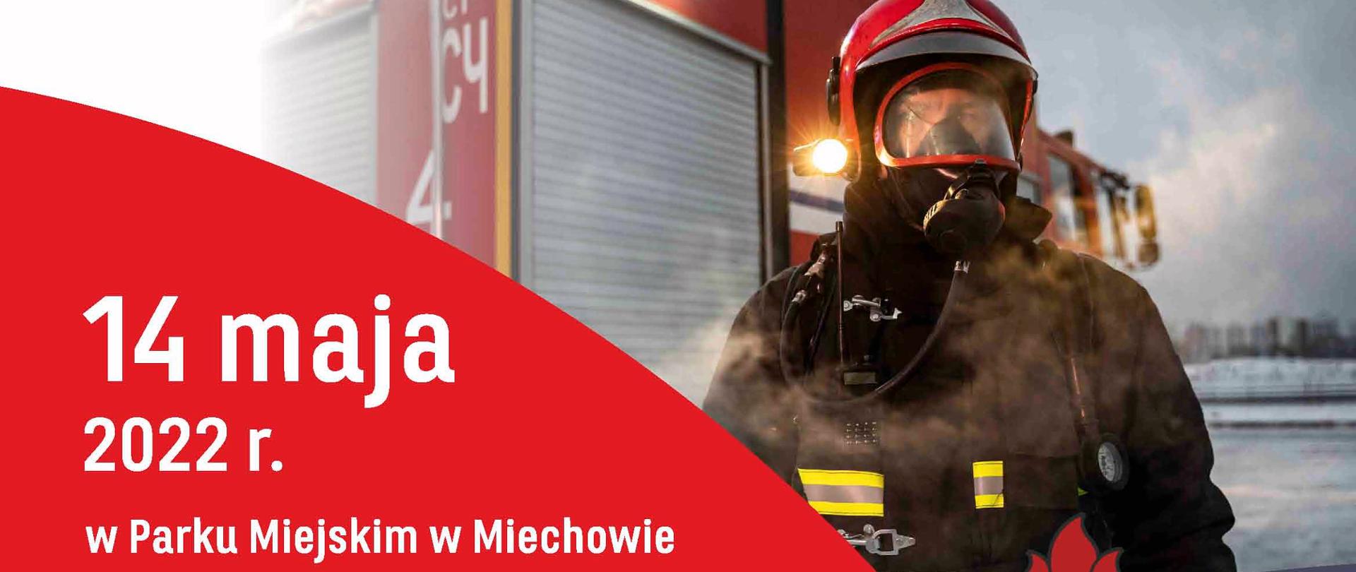 Strażak w ubraniu bojowym na tle samochodu pożarniczego. Plan uroczystości.